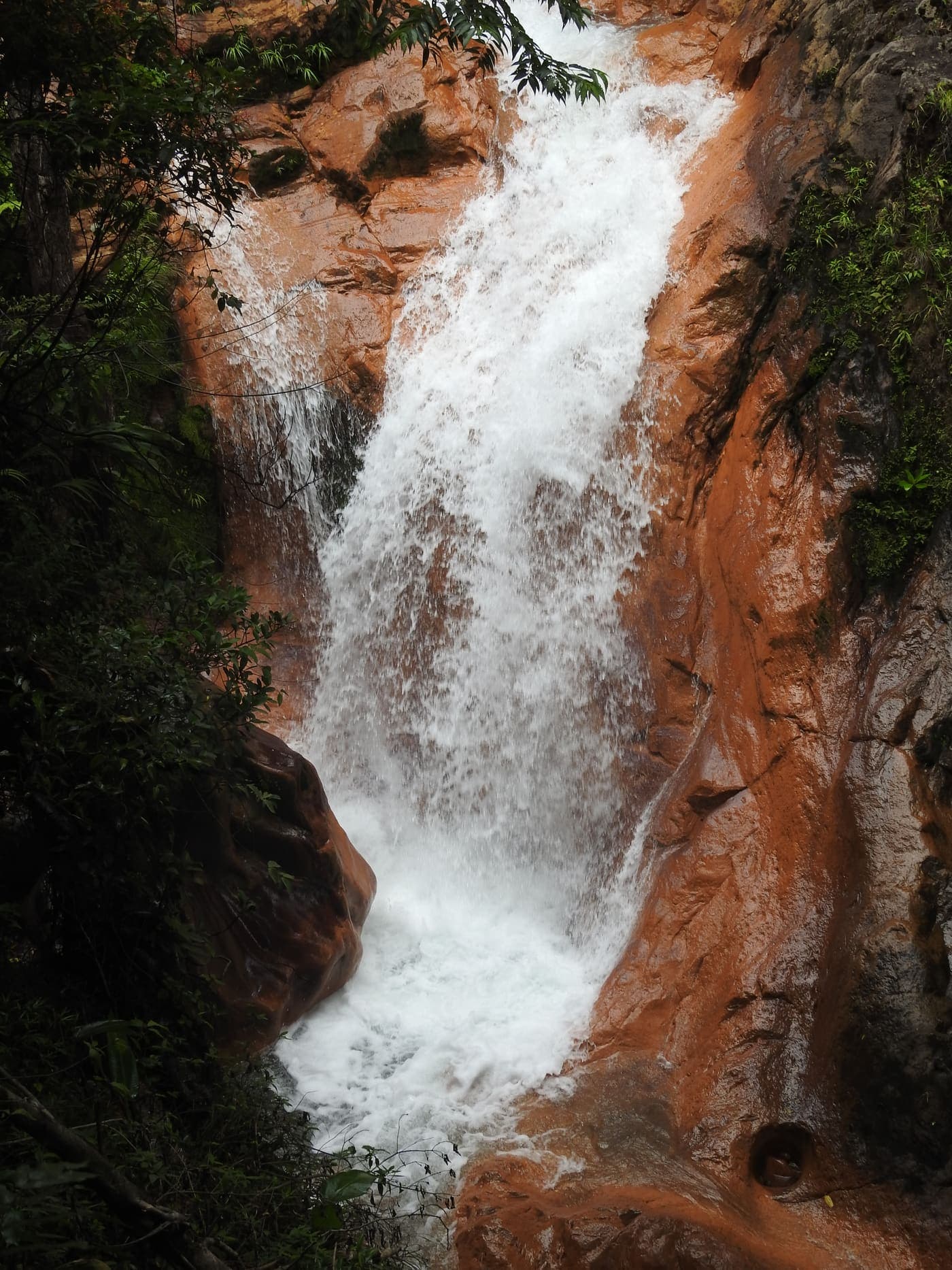 Cascada sobre roca volcánica rojiza